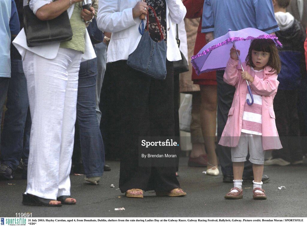 31 July 2003; Hayley Carolan, aged 4, from Donabate, Dublin, shelters from the rain during Ladies Day at the Galway Races. Galway Racing Festival, Ballybrit, Galway. Picture credit; Brendan Moran / SPORTSFILE *EDI*