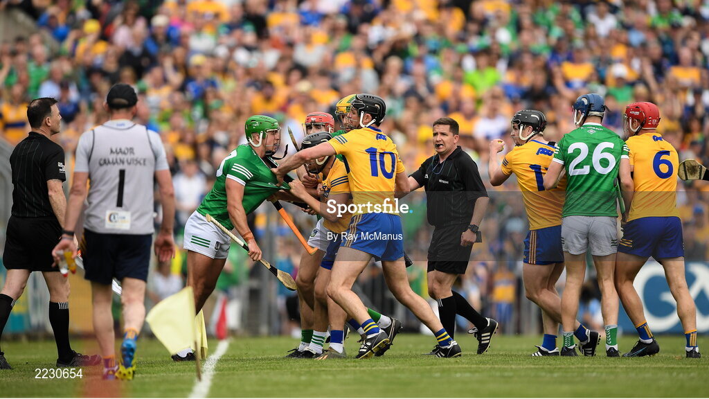 15 May 2022; Referee Colm Lyons looks on as players including David Reidy of Clare and Robbie Hanley of Limerick jostle during the Munster GAA Hurling Senior Championship Round 4 match between Clare and Limerick at Cusack Park in Ennis, Clare. Photo by Ray McManus/Sportsfile