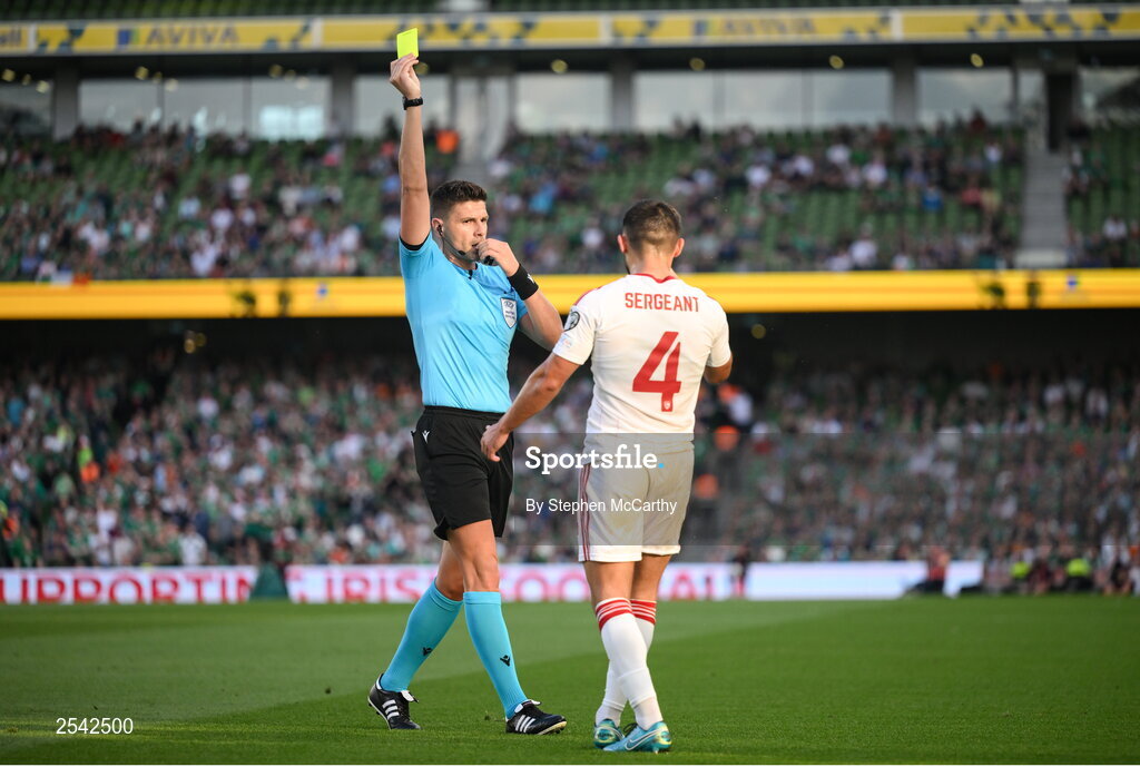19 June 2023; John Sergeant of Gibraltar is shown a yellow card by referee Marian Alexandru Barbu during the UEFA EURO 2024 Championship qualifying group B match between Republic of Ireland and Gibraltar at the Aviva Stadium in Dublin. Photo by Stephen McCarthy/Sportsfile