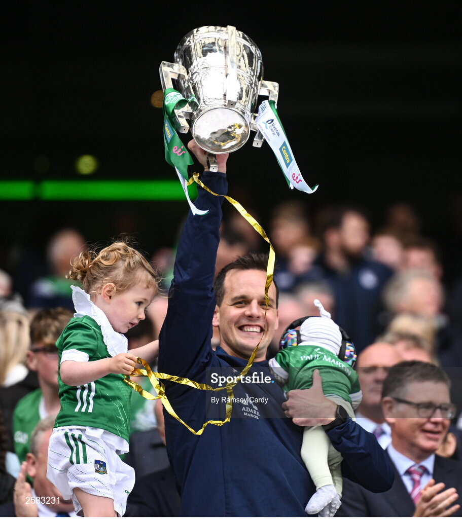 23 July 2023; Limerick selector Paul Kinnerk, with his children Paul, 4 weeks, and Enya, age 4, lifts the Liam MacCarthy Cup after the GAA Hurling All-Ireland Senior Championship final match between Kilkenny and Limerick at Croke Park in Dublin. Photo by Ramsey Cardy/Sportsfile