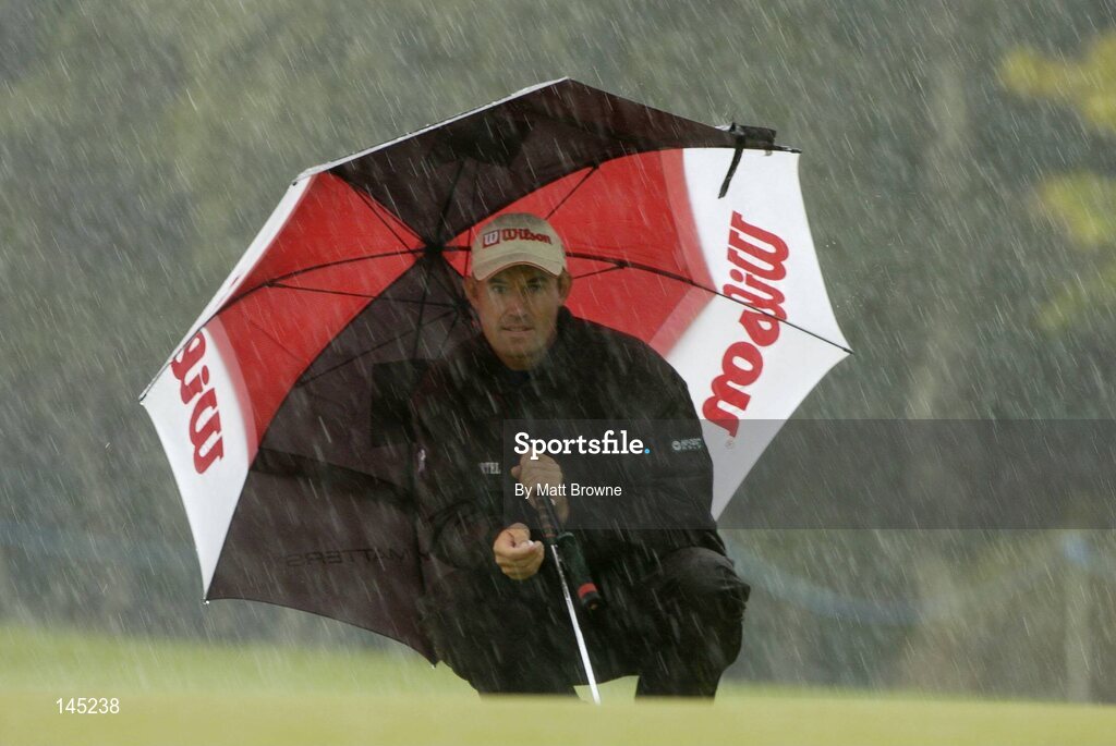 2 July 2004; Padraig Harrington takes cover from the rain on the 9th green during the Smurfit European Open. South Course, K Club, Straffan, Co. Kildare, Ireland. Picture credit; Matt Browne / SPORTSFILE