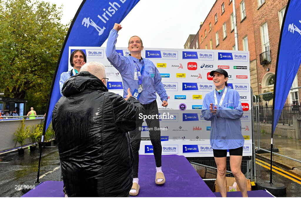 29 October 2023; Ann-Marie McGlynn is presented with the Women's National Championship trophy by Athletics Ireland President John Cronin after the 2023 Irish Life Dublin Marathon. Thousands of runners took to the Fitzwilliam Square start line, to participate in the 42nd running of the Dublin Marathon. Photo by Sam Barnes/Sportsfile