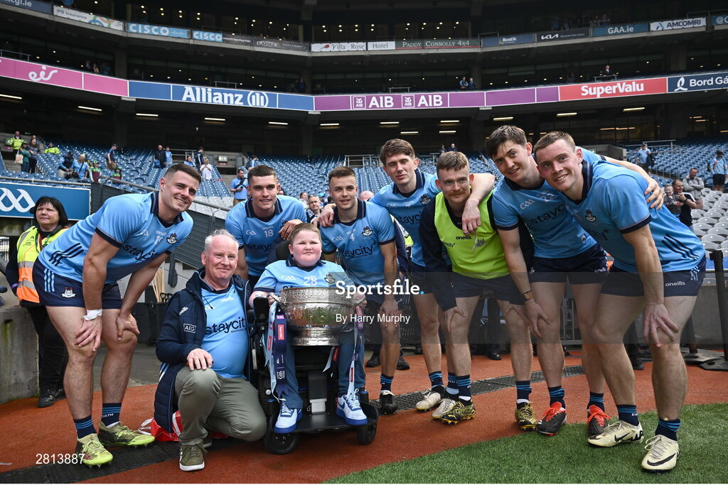12 May 2024; Dublin supporter Cathal Briscoe with the Delaney Cup and Dublin players after their side's victory in the Leinster GAA Football Senior Championship final match between Dublin and Louth at Croke Park in Dublin. Photo by Harry Murphy/Sportsfile