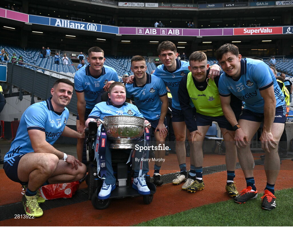 12 May 2024; Dublin supporter Cathal Briscoe with the Delaney Cup and Dublin players, from left, Brian Howard, Theo Clancy, Eoin Murchan, Michael Fitzsimons, Cian O’Connor and Killian McGinnis after their side's victory in the Leinster GAA Football Senior Championship final match between Dublin and Louth at Croke Park in Dublin. Photo by Harry Murphy/Sportsfile