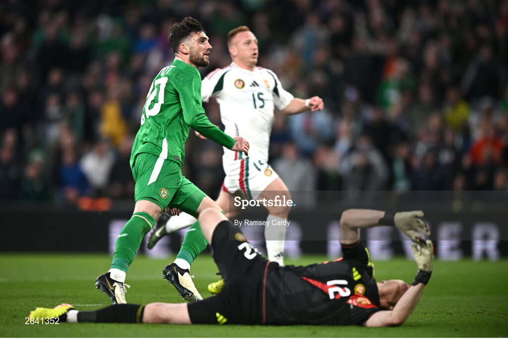 4 June 2024; Troy Parrott of Republic of Ireland and Hungary goalkeeper Dénes Dibusz look on as Troy Parrott scores his side's second goal during the international friendly match between Republic of Ireland and Hungary at Aviva Stadium in Dublin. Photo by Ramsey Cardy/Sportsfile