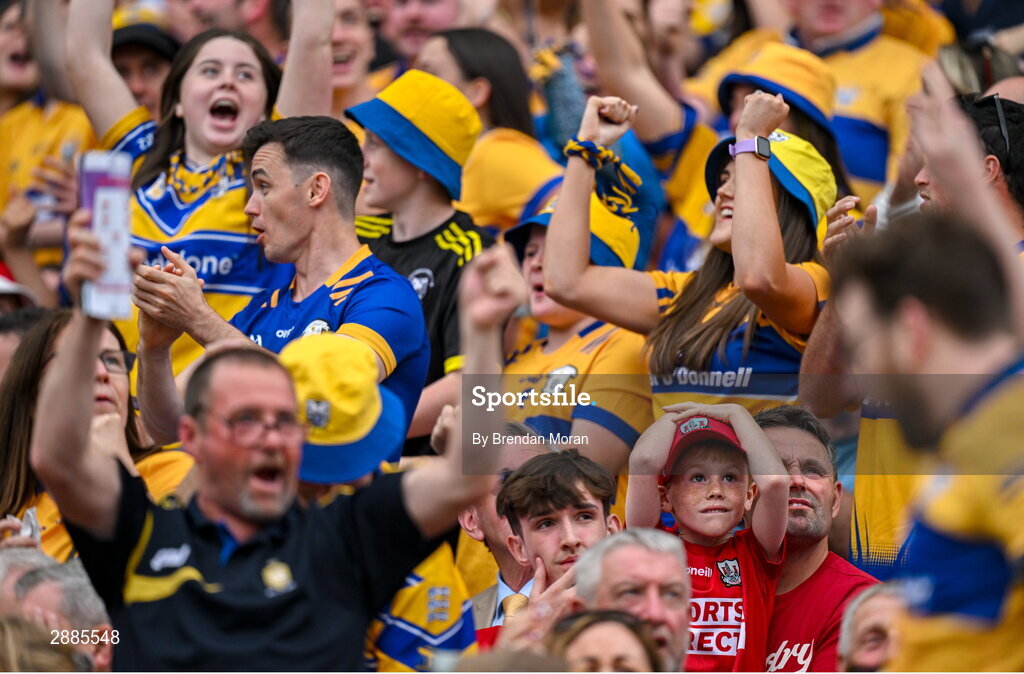 21 July 2024; Young Cork supporter Liam O'Donoghue and  his father William look on as Clare fans celebrate a score in extra time during the GAA Hurling All-Ireland Senior Championship Final between Clare and Cork at Croke Park in Dublin. Photo by Brendan Moran/Sportsfile