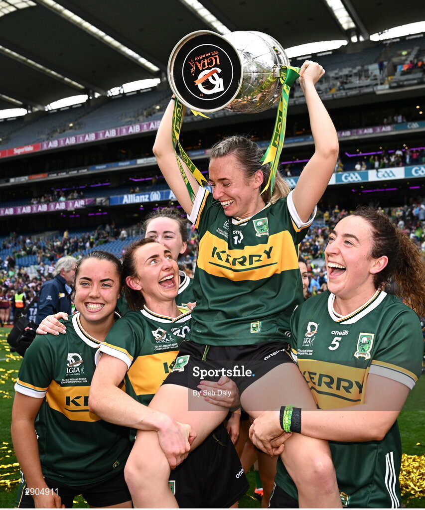 4 August 2024; Kerry captain Niamh Carmody celebrates with the the Brendan Martin cup as she is lifted up by teammates Cáit Lynch, left, and Kayleigh Cronin after their side's victory in the TG4 All-Ireland Ladies Football Senior Championship final match between Galway and Kerry at Croke Park, Dublin. Photo by Seb Daly/Sportsfile