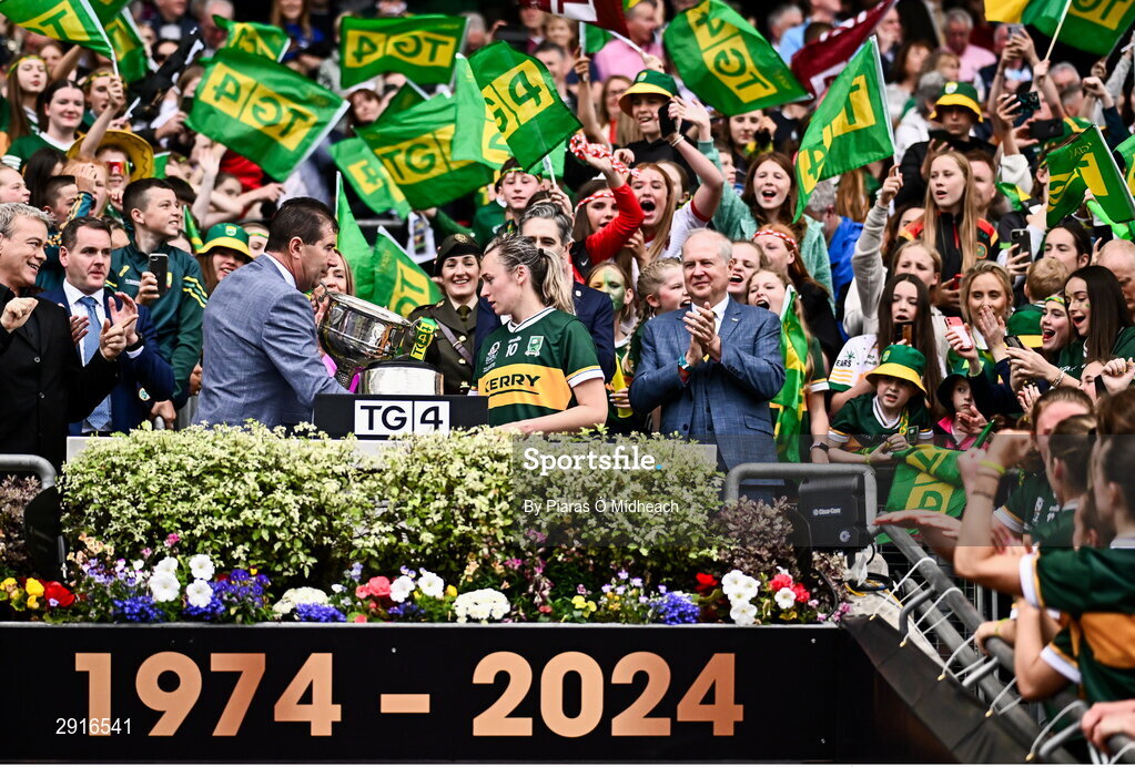 4 August 2024; Kerry captain Niamh Carmody is presented with the Brendan Martin Cup by Uachtarán Cumann Peil Gael na mBan Mícheál Naughton after her side's victory in the TG4 All-Ireland Ladies Football Senior Championship final match between Galway and Kerry at Croke Park in Dublin. Photo by Piaras Ó Mídheach/Sportsfile