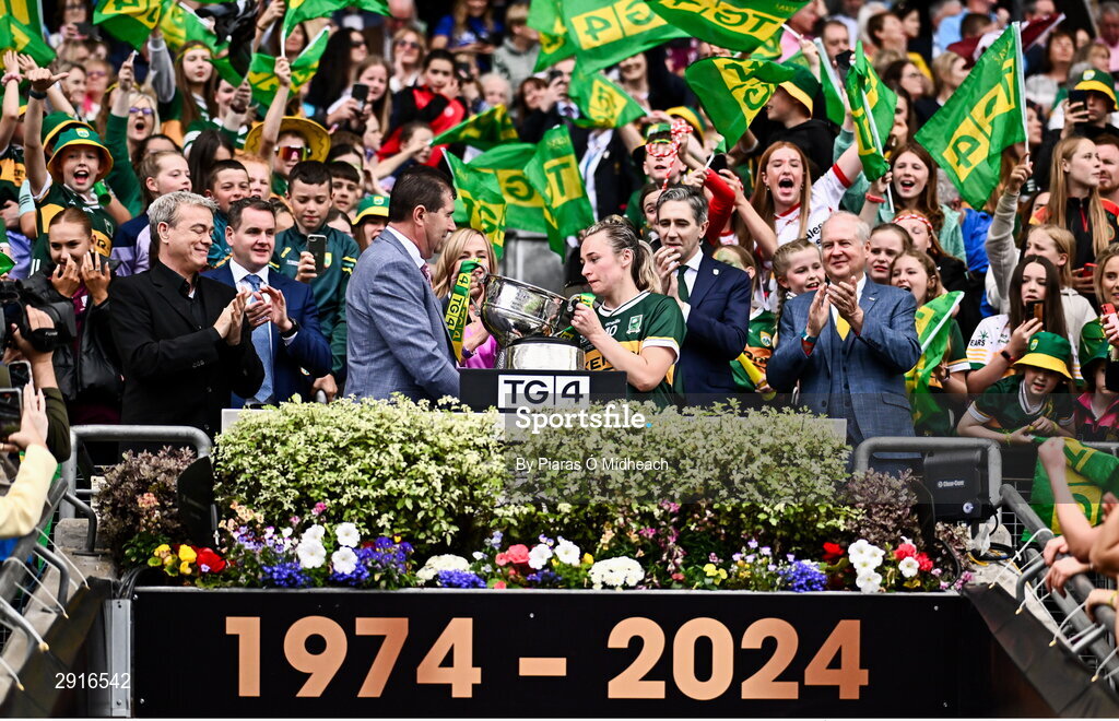 4 August 2024; Kerry captain Niamh Carmody is presented with the Brendan Martin Cup by Uachtarán Cumann Peil Gael na mBan Mícheál Naughton after her side's victory in the TG4 All-Ireland Ladies Football Senior Championship final match between Galway and Kerry at Croke Park in Dublin. Photo by Piaras Ó Mídheach/Sportsfile
