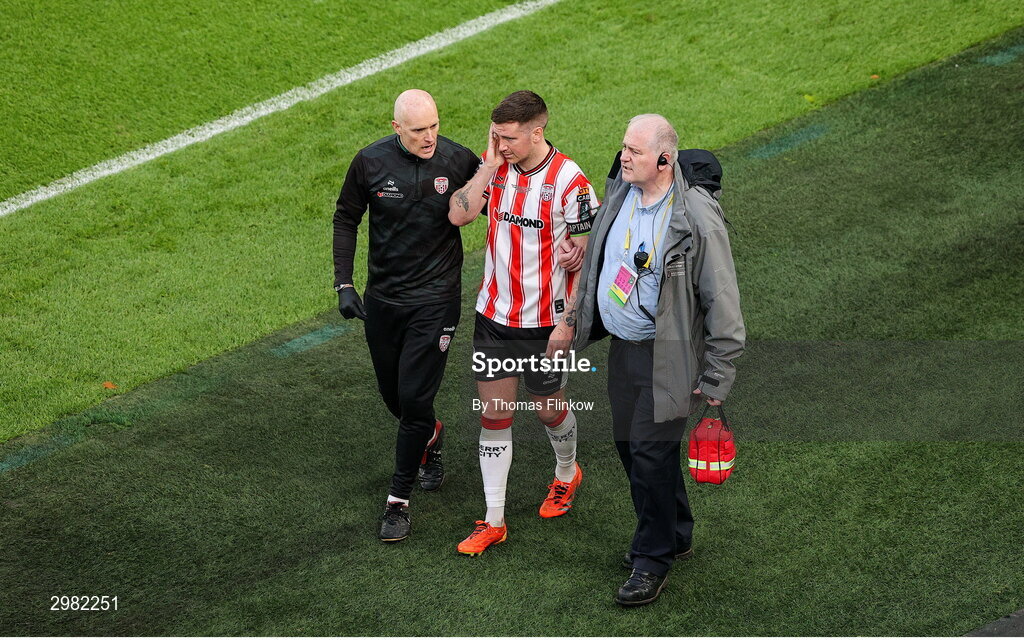 10 November 2024; Patrick McEleney of Derry City leaves the pitch to receive medical treatment, assisted by team doctor Neil McKeon and stadium doctor Mick Molloy, right, during the Sports Direct Men's FAI Cup Final match between Drogheda United and Derry City at the Aviva Stadium in Dublin. Photo by Thomas Flinkow/Sportsfile