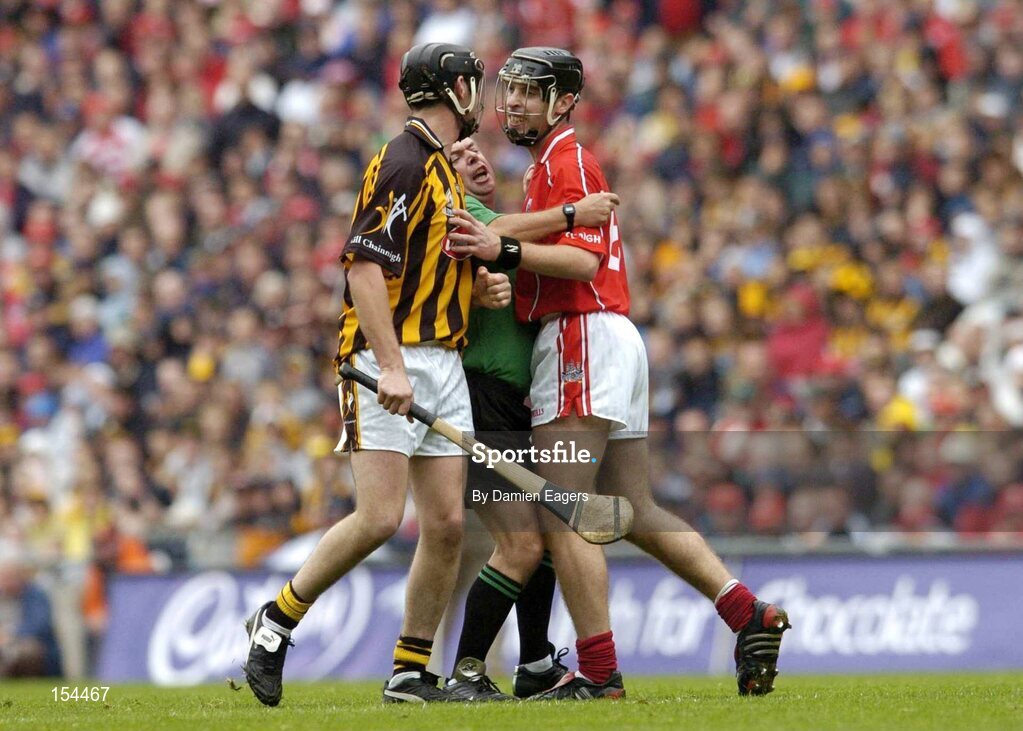 12 September 2004; Aidan MacSuibne, Referee, trys to separate Cork's Ronan Curran and Kilkenny's John Hoyne. Guinness All-Ireland Senior Hurling Championship Final, Cork v Kilkenny, Croke Park, Dublin. Picture credit; Damien Eagers / SPORTSFILE *** Local Caption *** Any photograph taken by SPORTSFILE during, or in connection with, the 2004 Guinness All-Ireland Hurling Final which displays GAA logos or contains an image or part of an image of any GAA intellectual property, or, which contains images of a GAA player/players in their playing uniforms, may only be used for editorial and non-advertising purposes.  Use of photographs for advertising, as posters or for purchase separately is strictly prohibited unless prior written approval has been obtained from the Gaelic Athletic Association.