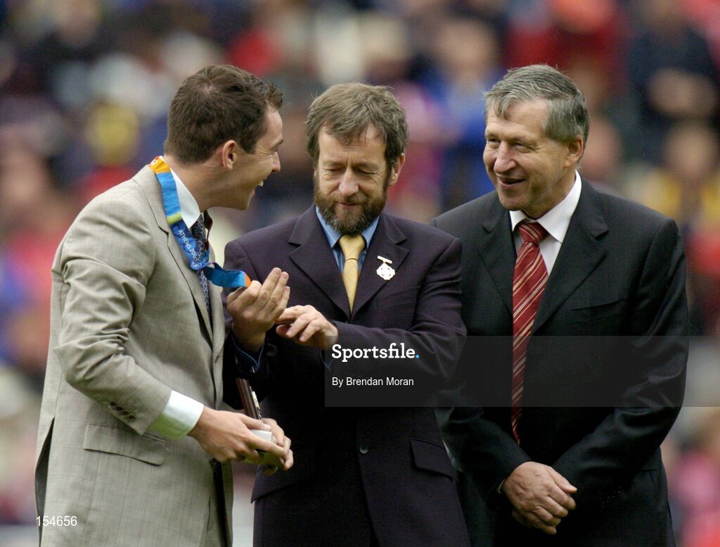 12 September 2004; President of the GAA Sean Kelly, centre, and Liam Mulvihill, Ard Stiurthoir of the GAA, admire the Gold Medal won by Irish Olympic Gold Medallist Cian O'Connor in Athens recently, after making a special presentation to him at half-time. Guinness All-Ireland Senior Hurling Championship Final, Cork v Kilkenny, Croke Park, Dublin. Picture credit; Brendan Moran / SPORTSFILE *** Local Caption *** Any photograph taken by SPORTSFILE during, or in connection with, the 2004 Guinness All-Ireland Hurling Final which displays GAA logos or contains an image or part of an image of any GAA intellectual property, or, which contains images of a GAA player/players in their playing uniforms, may only be used for editorial and non-advertising purposes.  Use of photographs for advertising, as posters or for purchase separately is strictly prohibited unless prior written approval has been obtained from the Gaelic Athletic Association.