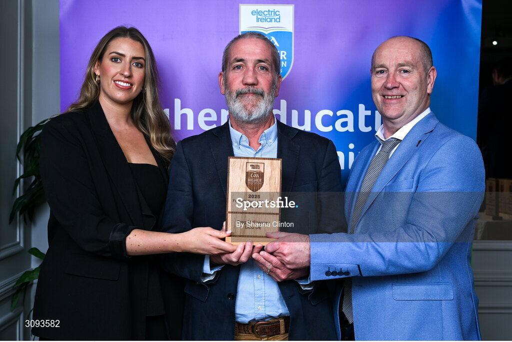 31 March 2025; Shane McEnaney, centre, father of DCU Dóchas Éireann player Greg McEnaney, not pictured, accepts the 2025 Electric Ireland Higher Education GAA Football Rising Stars Team of the Year award on behalf of his son, from Electric Ireland Sponsorship Manager Sarah Gelletlie, left, and Higher Education GAA Chairperson Benny Hurl during the Electric Ireland Higher Education Rising Stars Awards at Castleknock Hotel in Dublin. Photo by Shauna Clinton/Sportsfile