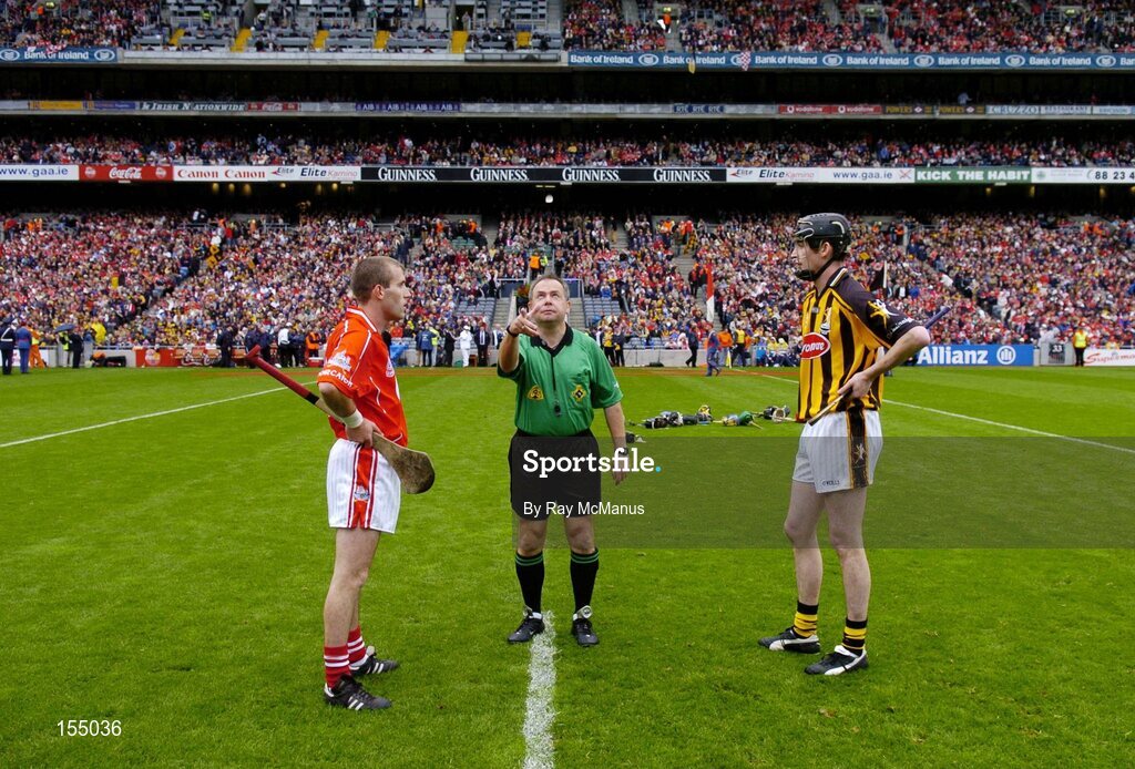 12 September 2004; Cork captain Ben O'Connor, left, and Kilkenny captain Martin Comerford look on as referee Aodan Mac Suibhne makes the toss. Guinness All-Ireland Senior Hurling Championship Final, Cork v Kilkenny, Croke Park, Dublin. Picture credit; Ray McManus / SPORTSFILE *** Local Caption *** Any photograph taken by SPORTSFILE during, or in connection with, the 2004 Guinness All-Ireland Hurling Final which displays GAA logos or contains an image or part of an image of any GAA intellectual property, or, which contains images of a GAA player/players in their playing uniforms, may only be used for editorial and non-advertising purposes.  Use of photographs for advertising, as posters or for purchase separately is strictly prohibited unless prior written approval has been obtained from the Gaelic Athletic Association.