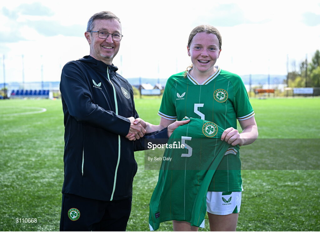 17 April 2025; Ruby Boland of Republic of Ireland is presented with her jersey by Republic of Ireland head coach Richard Berkeley after the Girls U15 SAFIB Bob Docherty Cup match between Northern Ireland and Republic of Ireland at Greenisland FC in Antrim. Photo by Seb Daly/Sportsfile