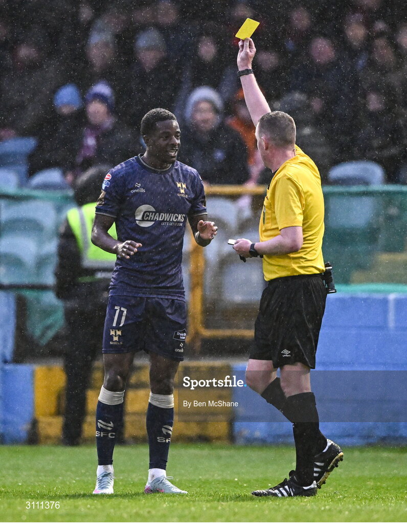 18 April 2025; Referee Damien MacGraith shows Mipo Odubeko of Shelbourne a yellow card during the SSE Airtricity Men's Premier Division match between Drogheda United and Shelbourne at Sullivan & Lambe Park in Drogheda, Louth. Photo by Ben McShane/Sportsfile