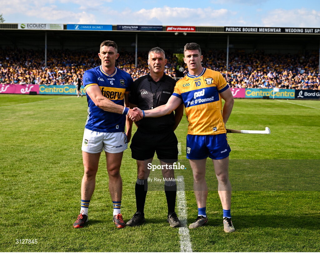 10 May 2025; Referee James Owens stands between the two captains, Ronan Maher of Tipperary and Tony Kelly of Clare, before the Munster GAA Hurling Senior Championship Round 3 match between Clare and Tipperary at Zimmer Biomet Páirc Chíosóg in Ennis, Clare. Photo by Ray McManus/Sportsfile