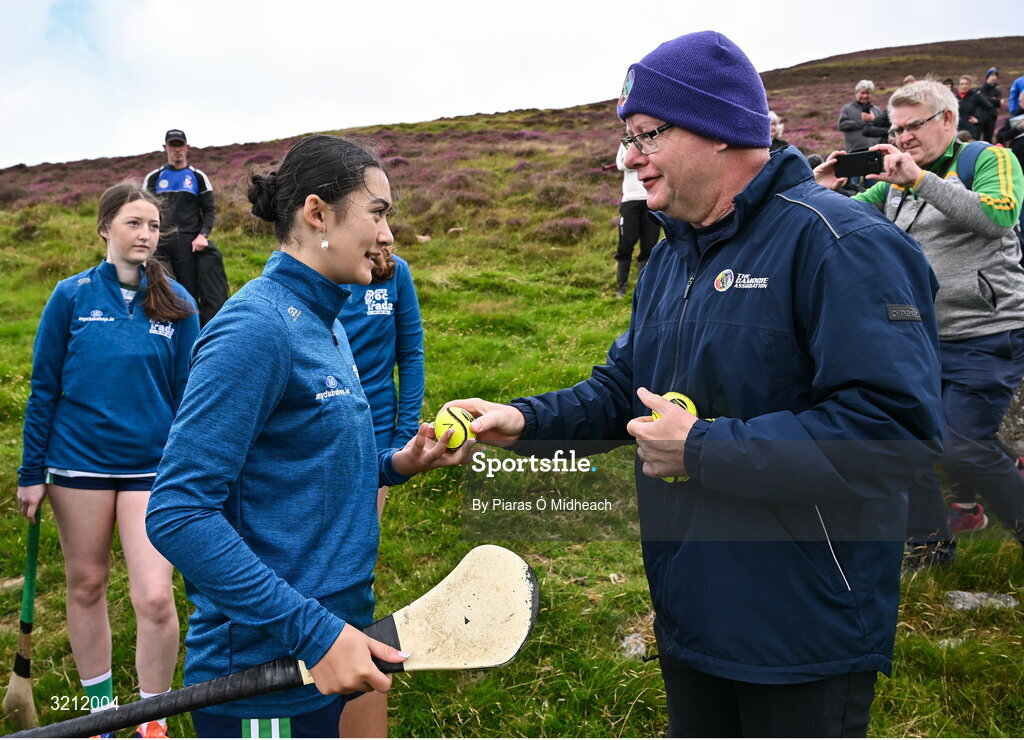 4 August 2025; Camogie Association president Brian Molloy presents a sliotar to Siofra Ginty of Offaly before the U16 camogie competition at the M. Donnelly GAA Poc Fada All-Ireland Finals at Annaverna Mountain in the Cooley Peninsula, Ravensdale, Louth. Photo by Piaras Ó Mídheach/Sportsfile