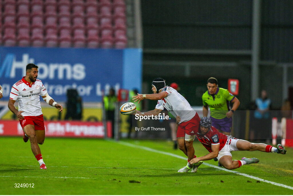 27 September 2025; Thaakir Abrahams of Munster passes the ball to Dan Kelly as he is tackled by Tom Rogers of Scarlets during the United Rugby Championship match between Scarlets and Munster at Parc Y Scarlets in Llanelli, Wales. Photo by Gruff Thomas/Sportsfile