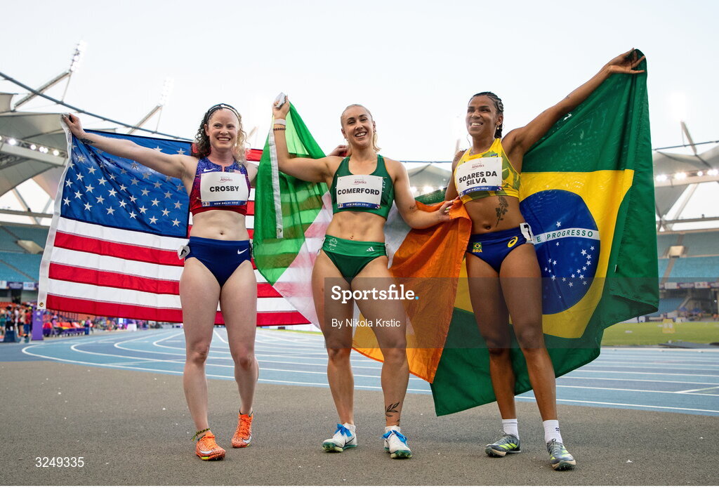 28 September 2025; Orla Comerford of team Ireland, centre, who won gold, Rayane Soares da Silva of Brazil, right, who won silver, and Kym Crosby of USA, who won bronze, celebrate after the Women's T13 100m final during day three of the New Delhi 2025 World Para Athletics Championships at JLN Stadium in New Delhi, India. Photo by Nikola Krstic/Sportsfile