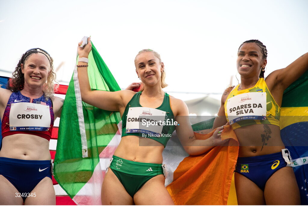 28 September 2025; Orla Comerford of team Ireland, centre, who won gold, Rayane Soares da Silva of Brazil, right, who won silver, and Kym Crosby of USA, who won bronze, celebrate after the Women's T13 100m final during day three of the New Delhi 2025 World Para Athletics Championships at JLN Stadium in New Delhi, India. Photo by Nikola Krstic/Sportsfile