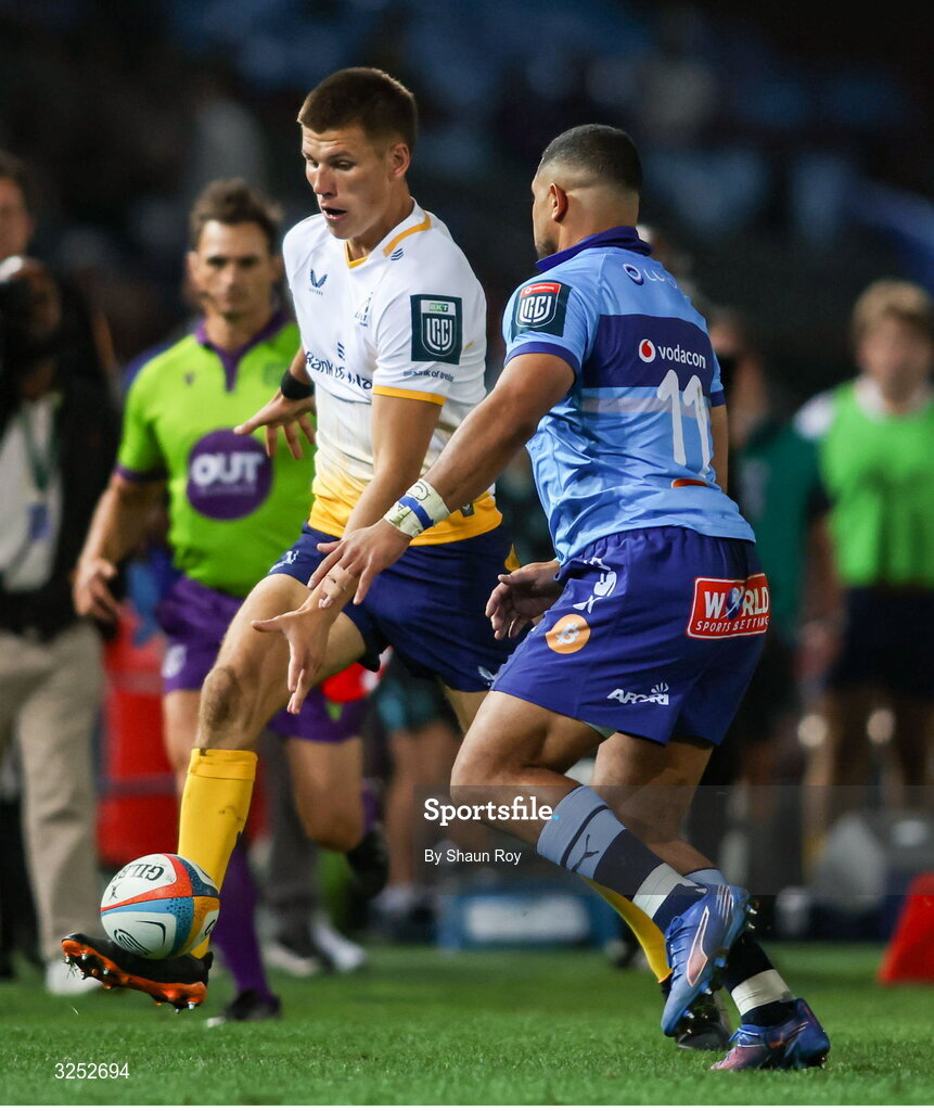 4 October 2025; Sam Prendergast of Leinster kicks on despite the attention of Stravino Jacobs of Vodacom Bulls during the United Rugby Championship match between Vodacom Bulls and Leinster at Loftus Versfeld Stadium in Pretoria, South Africa. Photo by Shaun Roy/Sportsfile
