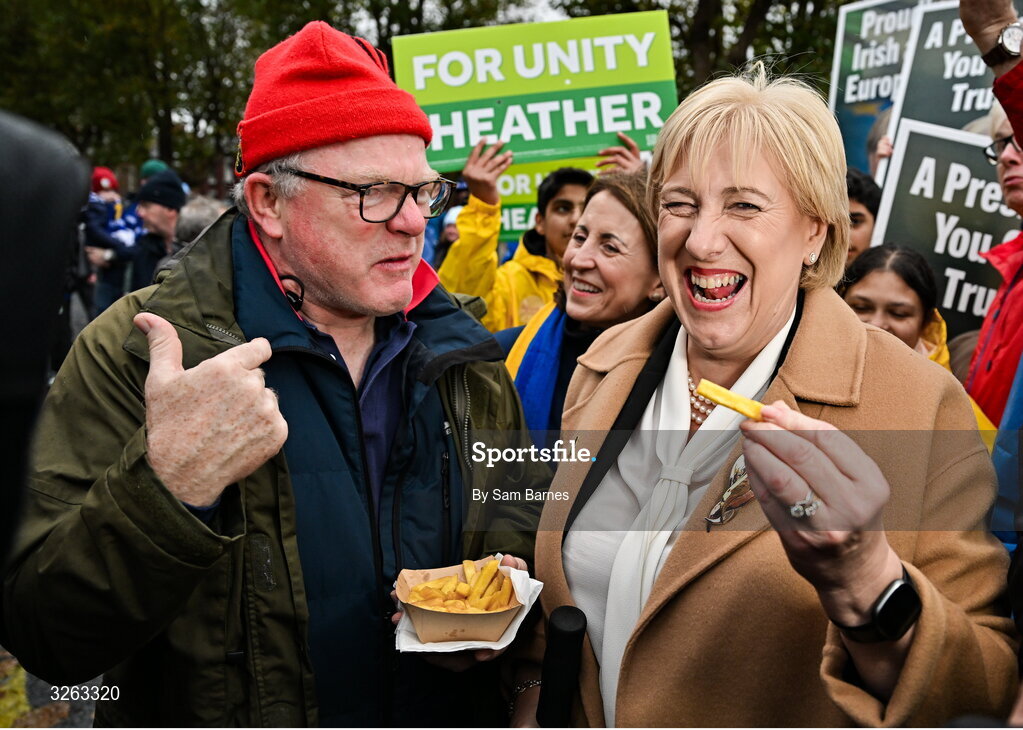 18 October 2025; Fine Gael presidential candidate Heather Humphreys, right, takes a chip from a Munster supporter before the United Rugby Championship match between Leinster and Munster at Croke Park in Dublin. Photo by Sam Barnes/Sportsfile