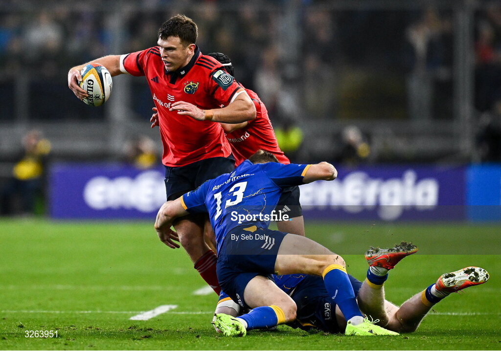 18 October 2025; Tom Farrell of Munster is tackled by Leinster players Garry Ringrose, 13, and Jamie Osborne during the United Rugby Championship match between Leinster and Munster at Croke Park in Dublin. Photo by Seb Daly/Sportsfile