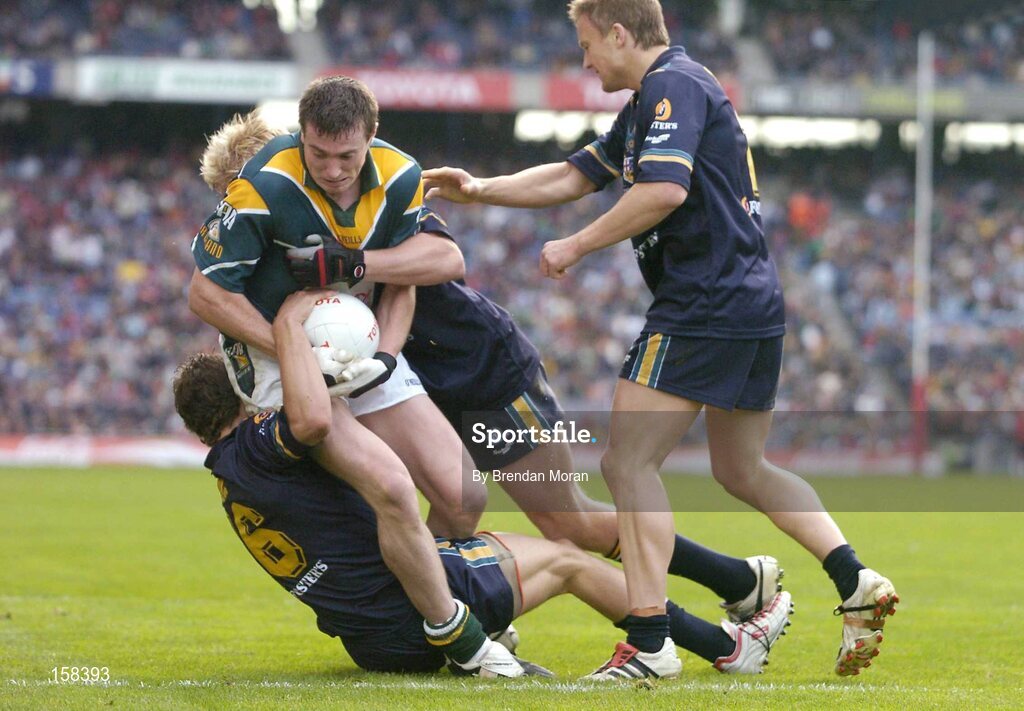 17 October 2004; Ciaran McManus, Ireland, is tackled by Craig Bolton and Adam McPhee, Australia. Coca Cola International Rules Series 2004, First Test, Ireland v Australia, Croke Park, Dublin. Picture credit; Brendan Moran / SPORTSFILE *** Local Caption *** Any photograph taken by SPORTSFILE during, or in connection with, the 2004 Coca Cola International Rules Series which displays GAA logos or contains an image or part of an image of any GAA intellectual property, or, which contains images of a GAA player/players in their playing uniforms, may only be used for editorial and non-advertising purposes.  Use of photographs for advertising, as posters or for purchase separately is strictly prohibited unless prior written approval has been obtained from the Gaelic Athletic Association.