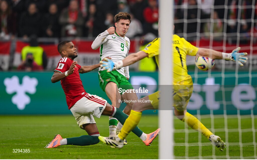16 November 2025; Johnny Kenny of Republic of Ireland shoots at goal under pressure from Hungary goalkeeper Dénes Dibusz and Loïc Négo, left, during the FIFA World Cup 2026 Group F Qualifier match between Hungary and Republic of Ireland at Puskás Aréna in Budapest, Hungary. Photo by Stephen McCarthy/Sportsfile
