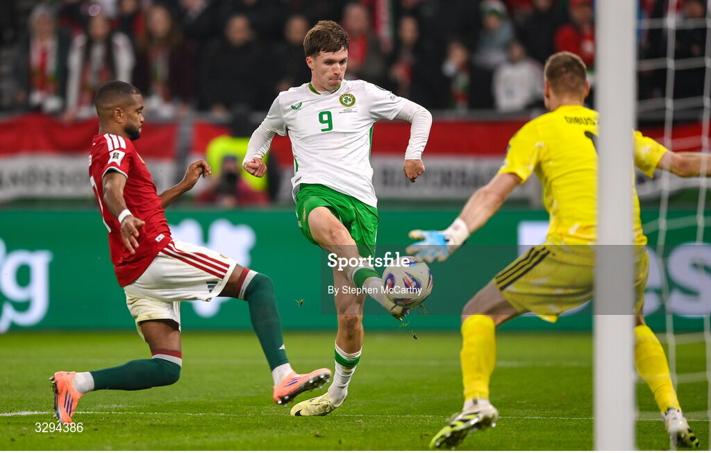 16 November 2025; Johnny Kenny of Republic of Ireland shoots at goal under pressure from Hungary goalkeeper Dénes Dibusz and Loïc Négo, left, during the FIFA World Cup 2026 Group F Qualifier match between Hungary and Republic of Ireland at Puskás Aréna in Budapest, Hungary. Photo by Stephen McCarthy/Sportsfile