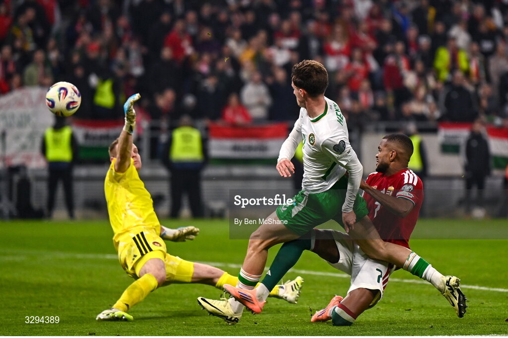 16 November 2025; Johnny Kenny of Republic of Ireland shoots at goal under pressure from Hungary goalkeeper Dénes Dibusz and Loïc Négo, left, during the FIFA World Cup 2026 Group F Qualifier match between Hungary and Republic of Ireland at Puskás Aréna in Budapest, Hungary. Photo by Ben McShane/Sportsfile