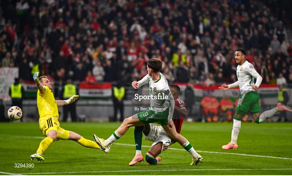16 November 2025; Johnny Kenny of Republic of Ireland shoots at goal under pressure from Hungary goalkeeper Dénes Dibusz and Loïc Négo, right, during the FIFA World Cup 2026 Group F Qualifier match between Hungary and Republic of Ireland at Puskás Aréna in Budapest, Hungary. Photo by Ben McShane/Sportsfile
