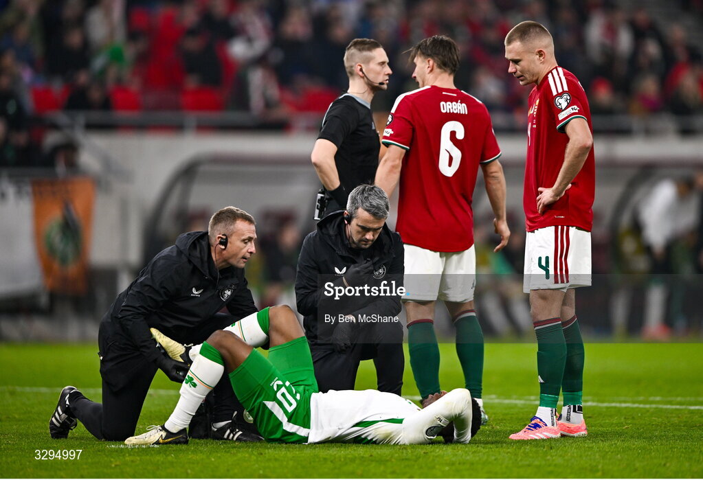 16 November 2025; Chiedozie Ogbene of Republic of Ireland is treated for an injury by lead physiotherapist Danny Miller, left, and team doctor Sean Carmody during the FIFA World Cup 2026 Group F Qualifier match between Hungary and Republic of Ireland at Puskás Aréna in Budapest, Hungary. Photo by Ben McShane/Sportsfile