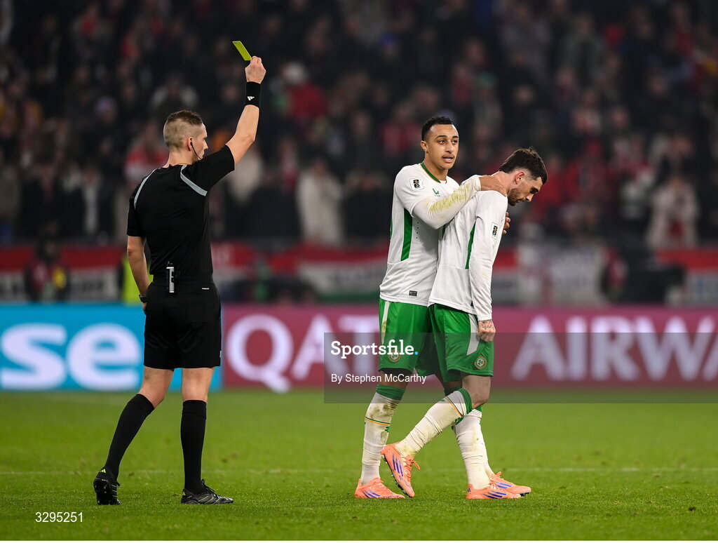 16 November 2025; Troy Parrott of Republic of Ireland, right, is shown a yellow card by referee Espen Eskas for removing his jersey in celebration after scoring his side's winning goal, as team-mate Adam Idah places an hand on his back during the FIFA World Cup 2026 Group F Qualifier match between Hungary and Republic of Ireland at Puskás Aréna in Budapest, Hungary. Photo by Stephen McCarthy/Sportsfile