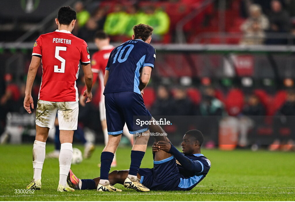 27 November 2025; Mipo Odubeko of Shelbourne is assisted with an injury by teammate John Martin during the UEFA Conference League 2025/26 league phase match between AZ Alkmaar and Shelbourne at AFAS Stadion in Alkmaar, Netherlands. Photo by Ben McShane/Sportsfile