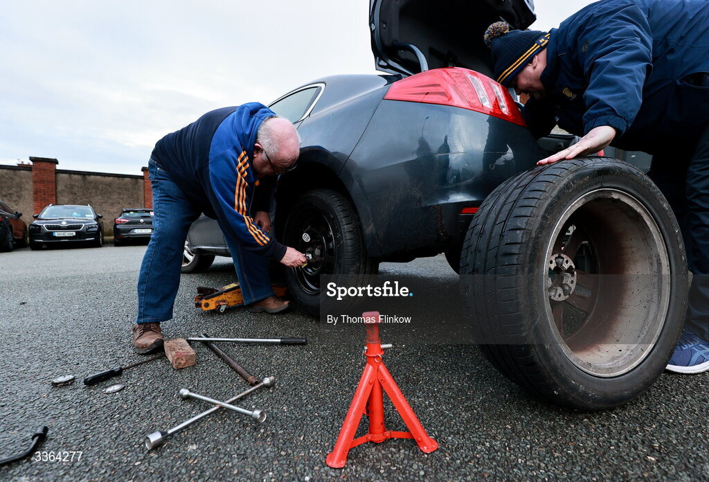 21 February 2026; Clare supporters Tom Sheehan, left, and Tom Keogh, both from Sixmilebridge in Clare, change a flat tyre outside the grounds before the Allianz Hurling League Division 1B match between Kildare and Clare at Cedral St Conleth's Park in Newbridge, Kildare. Photo by Thomas Flinkow/Sportsfile
