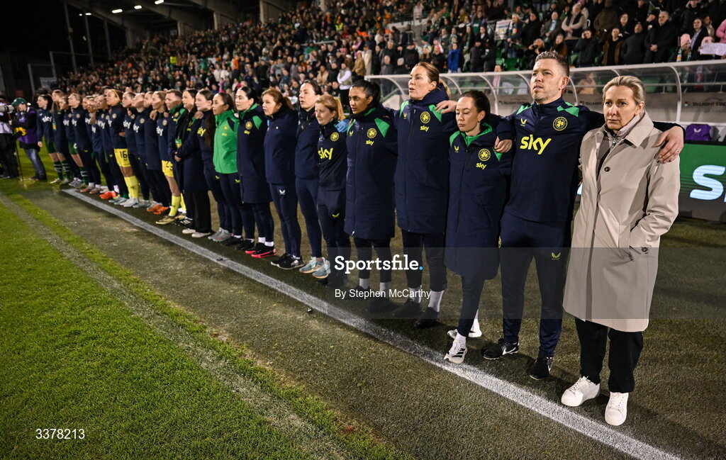 3 March 2026; Republic of Ireland head coach Carla Ward and backroom staff, from right, assistant coach Gary Cronin, assistant coach Amber Whiteley, goalkeeping coach Emma Byrne, performance analyst Jasmine Mander, performance coach Holly Pickett, physiotherapist Angela Kenneally, Dr Siobhan Forman, team doctor; physiotherapist Susie Coffey, performance nutritionist Olivia Patel, equipment officer Rachel O'Hanlon, team operations coordinator Denise McElhinney and equipment officer Barry Sanfey stand for Amhrán na bhFiann before the 2027 FIFA Women’s World Cup Qualifier match between Republic of Ireland and France at Tallaght Stadium in Dublin. Photo by Stephen McCarthy/Sportsfile