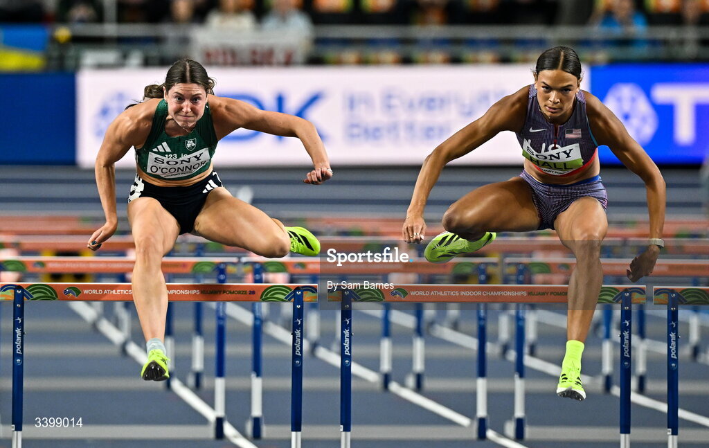 22 March 2026; Kate O'Connor of Ireland, left, and Anna Hall of United States compete in the Women's 60m hurdles event in the Women's Pentathlon during day three of the World Athletics Indoor Championships at Kujawsko-Pomorska Arena in Torun, Poland. Photo by Sam Barnes/Sportsfile