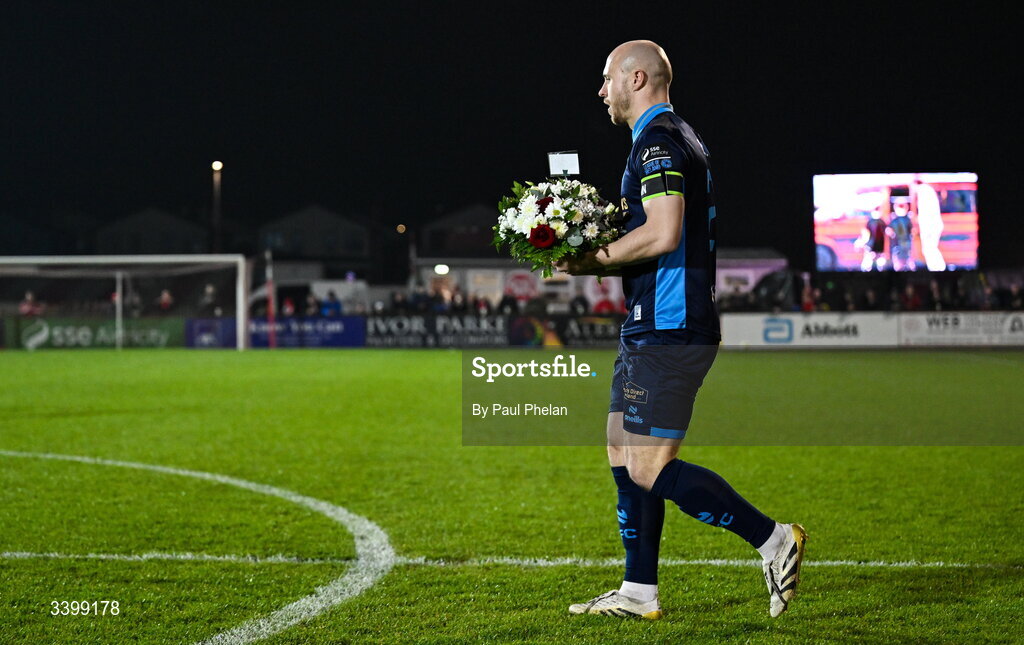 21 March 2026; Kerr McInroy of Shelbourne walks flowers to place in the centre circle in memory of Sligo Rovers supporter Aaron Mulligan before the SSE Airtricity Men's Premier Division match between Sligo Rovers and Shelbourne at The Showgrounds in Sligo. Photo by Paul Phelan/Sportsfile