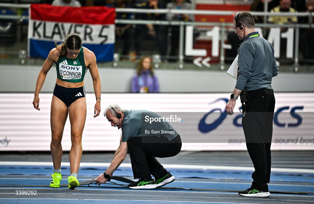 22 March 2026; Kate O'Connor of Ireland in conversation with officials to move cables and repair the track before competing in the Women's high jump event in the Women's Pentathlon during day three of the World Athletics Indoor Championships at Kujawsko-Pomorska Arena in Torun, Poland. Photo by Sam Barnes/Sportsfile