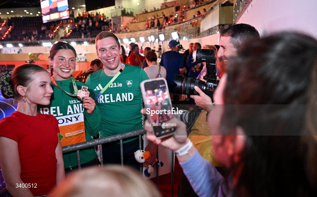 22 March 2026; Women's Pentathlon bronze medallist Kate O'Connor of Ireland, left, and Athletics Ireland Team Press Liason Rory Cassidy pose for photos with supporters after day three of the World Athletics Indoor Championships at Kujawsko-Pomorska Arena in Torun, Poland. Photo by Sam Barnes/Sportsfile
