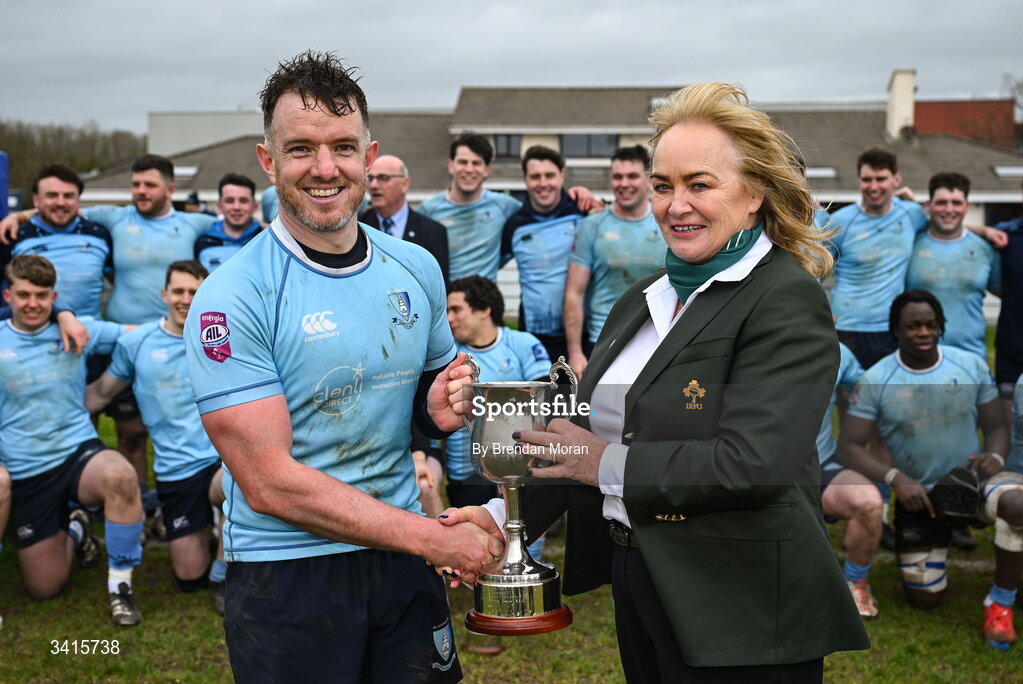 4 April 2026; MU Barnhall captain Rob Holt is presented with the Energia AIL Division 2 trophy by IRFU committee member Grainne Carroll after the Energia Men's All-Ireland League Division match between MU Barnhall and Wanderers RFC at MU Barnhall RFC in Parsonstown, Kildare. Photo by Brendan Moran/Sportsfile