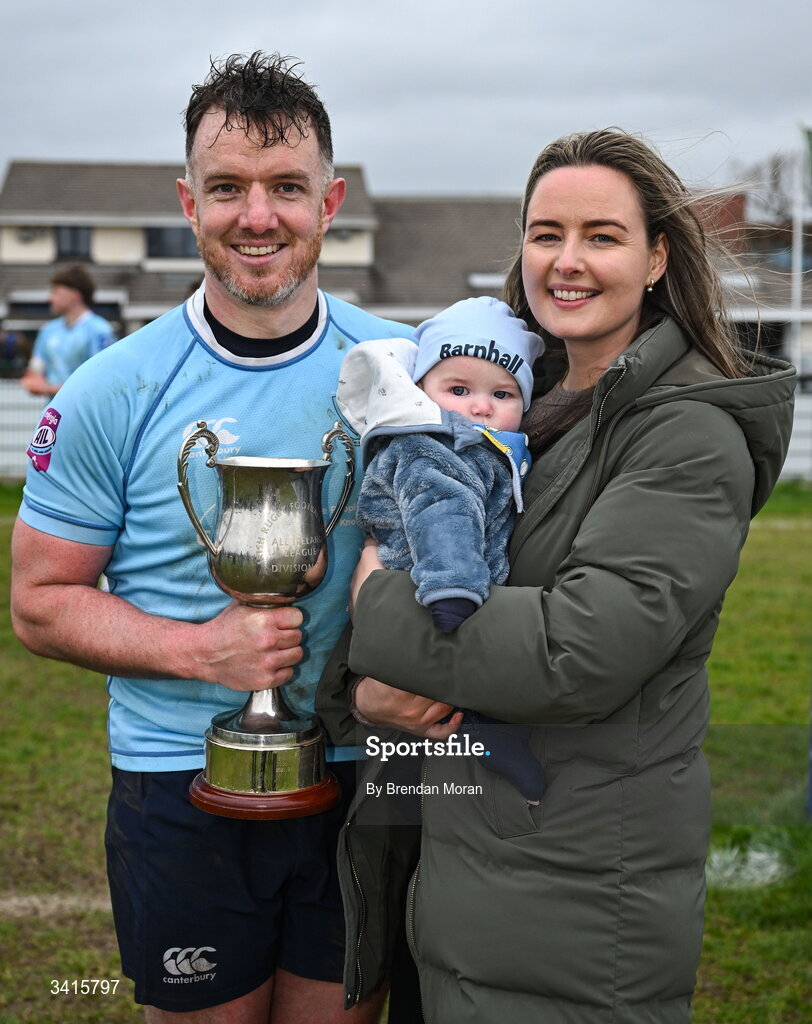4 April 2026; MU Barnhall captain Rob Holt celebrates with his son Tadhg and wife Amy and the Energia AIL Division 2 trophy after the Energia Men's All-Ireland League Division match between MU Barnhall and Wanderers RFC at MU Barnhall RFC in Parsonstown, Kildare. Photo by Brendan Moran/Sportsfile