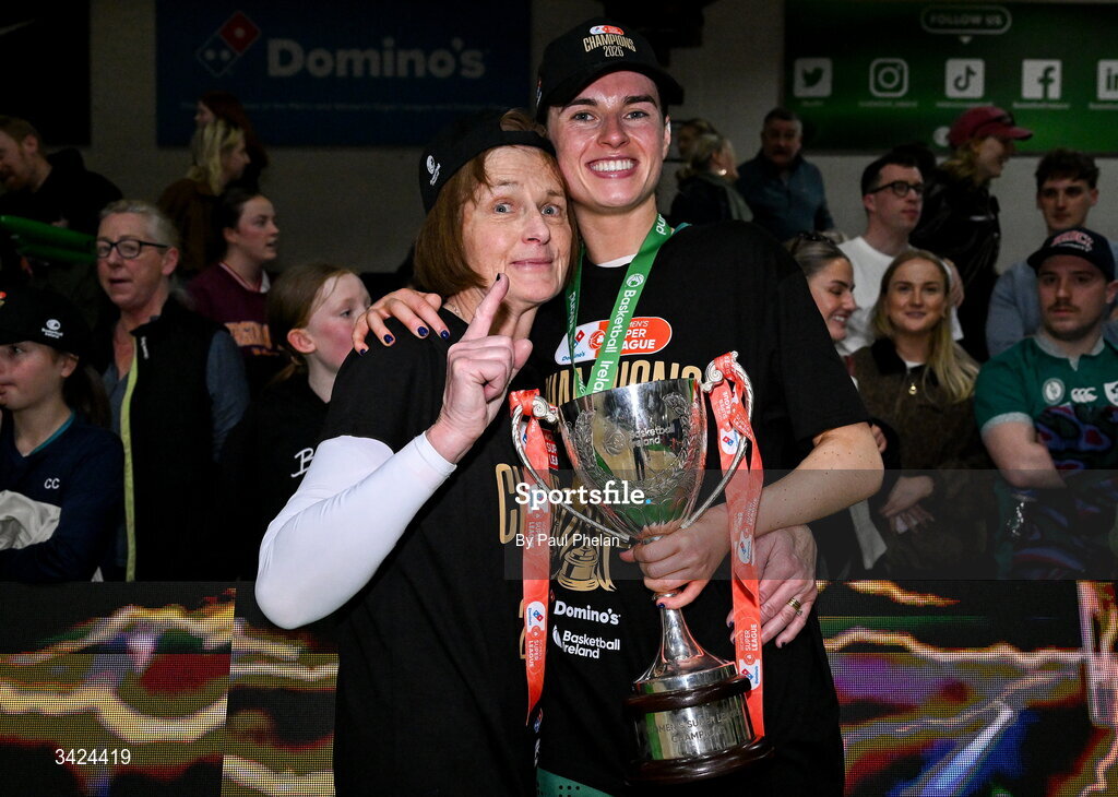12 April 2026; The captain of Trinity Meteors, Catherine Connaire, centre, celebrates with the cup and with her mother, Mags Connaire, left after the Basketball Ireland Women's Superleague final match between Trinity Meteors and UCC Glanmire at the National Basketball Arena in Tallaght, Dublin. Photo by Paul Phelan/Sportsfile
