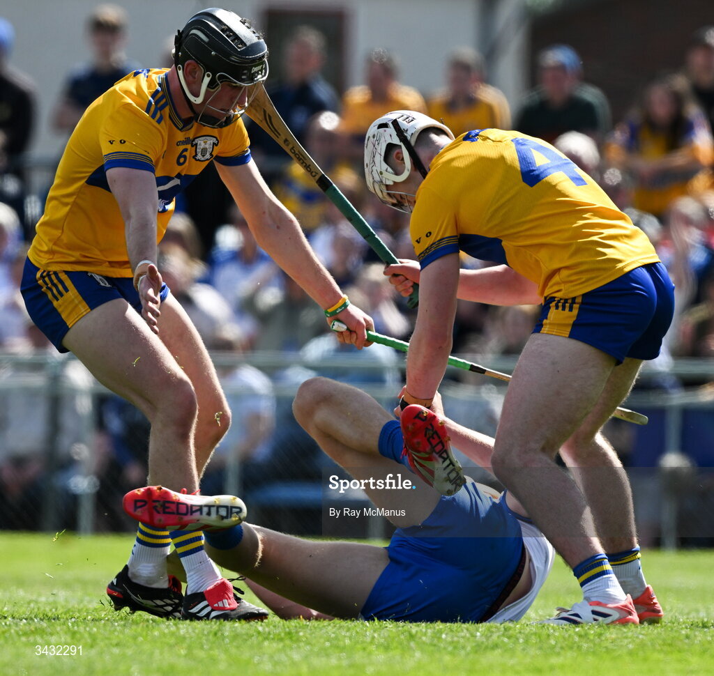 19 April 2026; Sean Walsh of Waterford is tackled by Niall O'Farrell and Adam Hogan of Clare, 4, to win a penalty during the Munster GAA Senior Hurling Championship Round 1 match between Clare and Waterford at Zimmer Biomet Páirc Chíosóg in Ennis, Clare. Photo by Ray McManus/Sportsfile