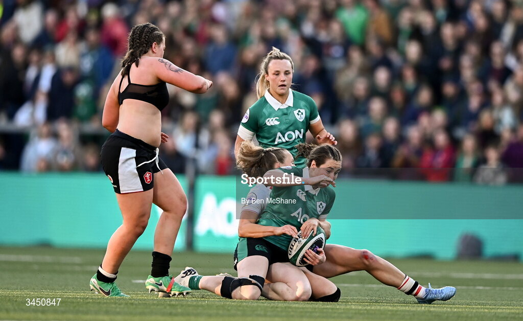 9 May 2026; Eve Higgins of Ireland is tackled by Carys Cox of Wales, as Maisie Davies of Wales, left, plays on without a shirt during the Women's 6 Nations Rugby Championship match between Ireland and Wales at Affidea Stadium in Belfast. Photo by Ben McShane/Sportsfile