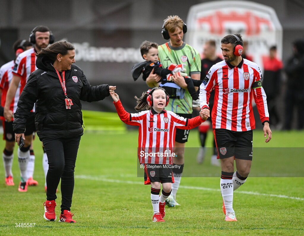 12 June 2026; Derry City captain Michael Duffy wears ear defenders as part of a Derry City awareness initiative while walking out with Karen Pyne and her daughter Eimile before the SSE Airtricity Men’s Premier Division match between Derry City and Bohemians at Find Insurance Celtic Park in Derry. Photo by Stephen McCarthy/Sportsfile