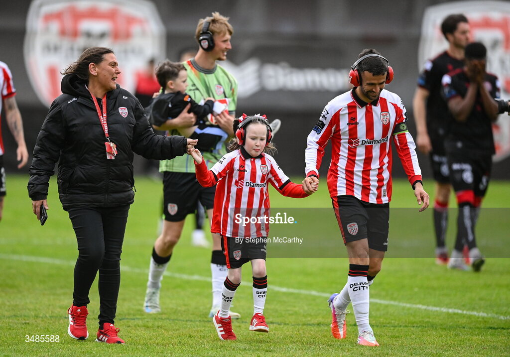 12 June 2026; Derry City captain Michael Duffy wears ear defenders as part of a Derry City awareness initiative while walking out with Karen Pyne and her daughter Eimile before the SSE Airtricity Men’s Premier Division match between Derry City and Bohemians at Find Insurance Celtic Park in Derry. Photo by Stephen McCarthy/Sportsfile