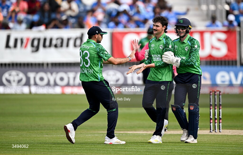 26 June 2026; Ireland bowler Matthew Humphreys, centre, is congratulated by teammates Lorcan Tucker, right, and Liam McCarthy after taking the wicket of India batter Tilak Varma during match one of the Spinny Cup Men's T20 International series between Ireland and India at Stormont in Belfast. Photo by Seb Daly/Sportsfile